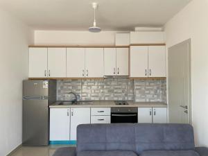 a kitchen with white cabinets and a gray refrigerator at Nimfeum Apartments in Shëngjin