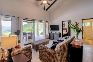 a living room with a couch and chairs and a television at Casa La Cascada in Dominical
