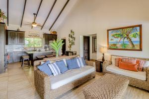 a living room with wicker furniture and a kitchen at Casa La Cascada in Dominical