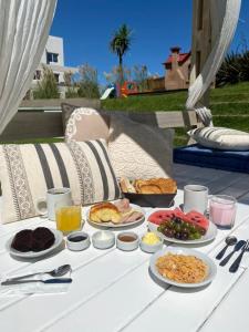 a white table with plates of food on it at Valeria Playa Apart in Valeria del Mar