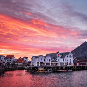 a group of houses on a dock with a sunset at Villa Bryggekanten - by Classic Norway Hotels in Henningsvær