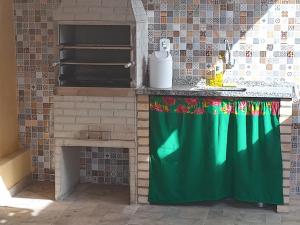 - une cuisine avec une cuisinière et un rideau vert dans l'établissement Casa da Celia 02, à Arraial do Cabo