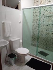La salle de bains est pourvue de toilettes et d'une douche en verre. dans l'établissement Casa da Celia 02, à Arraial do Cabo
