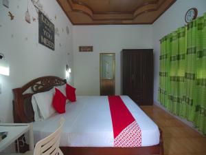 a bedroom with a bed with red and green sheets at OYO 771 Darius' Residences in Moalboal
