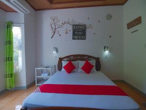 a bedroom with a bed with red pillows at OYO 771 Darius' Residences in Moalboal
