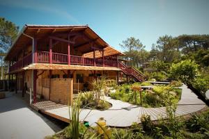 a wooden building with a balcony and a garden at les jardins de la sud in Lacanau