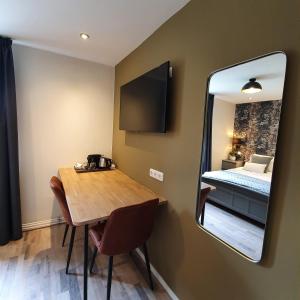 een kamer met een tafel, een spiegel en een bed bij Luxe B&B Vroelen-Noorbeek in Noorbeek