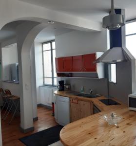 a kitchen with red cabinets and a wooden table at L'ère du temps in Manheulles