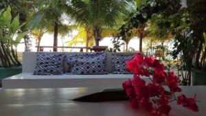 un banc blanc avec des fleurs rouges sur une table dans l'établissement Oceano Atins, à Atins