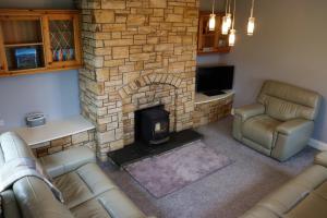 a living room with a fireplace and a couch and chair at Mount Alohert House in Killarney