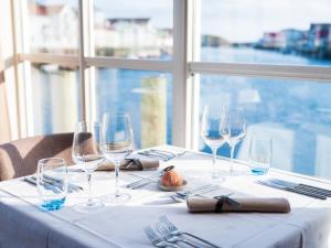 a table with wine glasses and silverware on it at Villa Bryggekanten - by Classic Norway Hotels in Henningsvær
