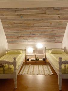 two beds in a bedroom with a wooden wall at Holiday Home Green House in Divčibare