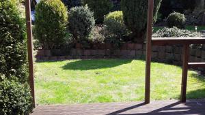 a garden with a lawn with a fence and a wooden bench at Willkommen im Kalletal in Kalletal