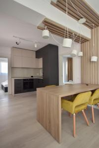 een keuken met een houten tafel en gele stoelen bij WAVE 3 Promenada Apartments in Mamaia Nord – Năvodari