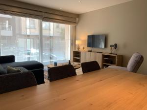 uma sala de estar com uma mesa e cadeiras e uma televisão em Bleu Soleil em Knokke-Heist