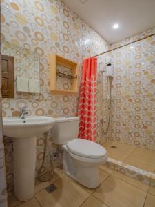 Un baño con inodoro, lavabo y ducha. en Jurias Garden Hotel, en El Nido
