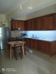 a kitchen with wooden cabinets and a table and a refrigerator at Joanna 's Loft in Kissamos