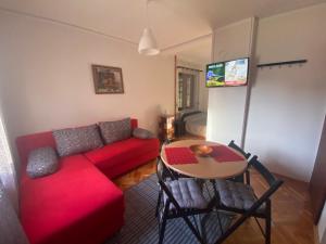 a living room with a red couch and a table at Ozrenska bašta apartmani in Soko Banja