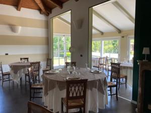 un comedor con mesas, sillas y ventanas en La Foresteria Canavese Golf & Country Club, en Torre Canavese