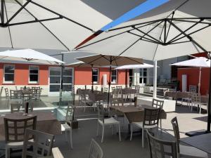 an outdoor patio with tables and chairs and umbrellas at La Foresteria Canavese Golf & Country Club in Torre Canavese