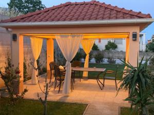 un patio con mesa y sillas bajo una pérgola en Apartment Vedran, en Kaštela