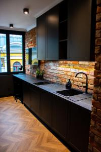 a kitchen with black cabinets and a brick wall at Apartamenty Stare Miasto in Zamość