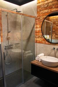 a bathroom with a shower with a sink and a mirror at Apartamenty Stare Miasto in Zamość