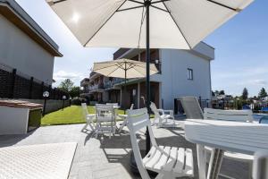 a patio with white chairs and tables and an umbrella at Valmontone Travel Rooms in Valmontone