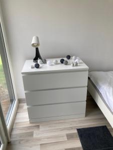 a white dresser with a lamp on it next to a bed at Cisy Resort-idealny dla gości ze zwierzętami,ogrodzony teren na wyłączność,150 m od jeziora in Ełk