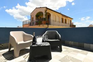 two chairs and a table with wine glasses and a building at Urban Blue Guest House in Olbia