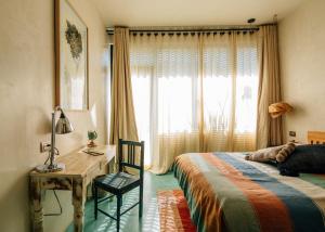a bedroom with a bed and a desk and a window at Boulenc Bed and Bread in Oaxaca City