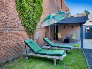 um grupo de cadeiras e um guarda-sol num quintal em Modern holiday home in Scherpenheuvel with infrared sauna em Scherpenheuvel-Zichem