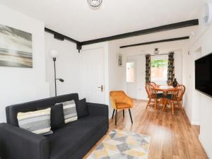 a living room with a black couch and a table at Oar Cottage in Mablethorpe