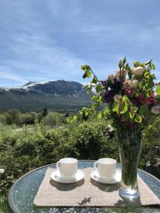 una mesa con dos tazas y un jarrón con flores en Private apartments!Oppdal Alpintun, Skisenter-Stølen en Oppdal