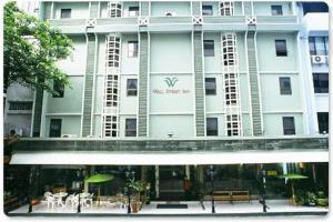 un gran edificio blanco con mesas y sillas delante de él en Wall Street Inn, Bangkok, en Bangkok