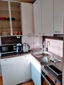 a white kitchen with a sink and a microwave at Scandi FoRest in Palanga