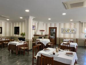 restauracja ze stołami i krzesłami z białym blatem w obiekcie Hotel Casa Portuguesa w mieście Meaño