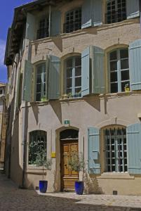 un bâtiment avec des fenêtres vertes à volets et une porte dans l'établissement In Situ B&B, à Uzès