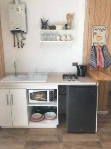 a small kitchen with a microwave and a sink at Apart Hotel Don Domingo Coñaripe in Coñaripe