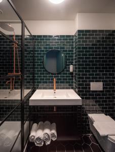 a black tiled bathroom with a sink and a mirror at FD Hotels in Rotterdam