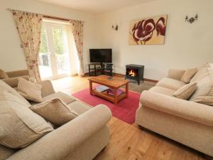 sala de estar con 2 sofás y chimenea en Gardener's Cottage, en Belford