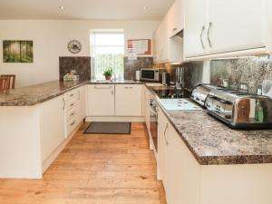 - une cuisine avec des placards blancs et des comptoirs en marbre dans l'établissement Gardener's Cottage, à Belford