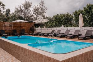 a swimming pool with chairs and umbrellas on a patio at Villa "White Pearl" in Zatoka