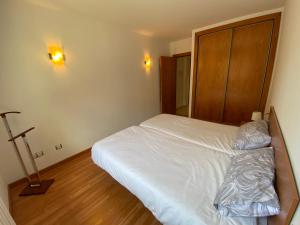 una camera con letto bianco e testiera in legno di Residencial Sol i Ski 24 4p Ransol El Tarter Zona Grandvalira a Sant Pere