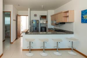 une cuisine avec un comptoir et quatre tabourets dans l'établissement Hermoso Apartamento Frente al Mar 2 Habitaciones PAZ148, à Coveñitas