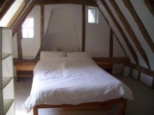 a bedroom with a white bed with two windows at Burnt House Cottage in Barking