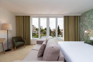 1 dormitorio con cama, sofá y ventana en Casa de Arouca Porto Apartments en Oporto