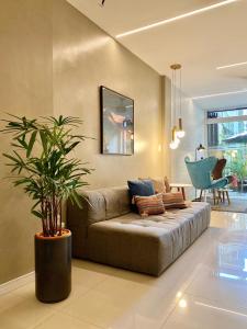 a living room with a couch and a potted plant at Injoy Suítes & Aparts in Rio de Janeiro