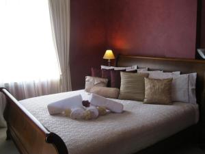 a bed with a white comforter and pillows on it at Heritage Guesthouse in South West Rocks
