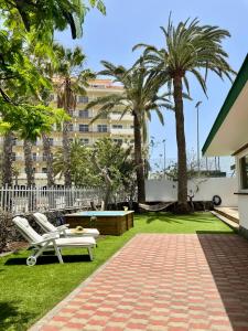 a park with two white chairs and palm trees at Confortable independent Villa in San Agustin